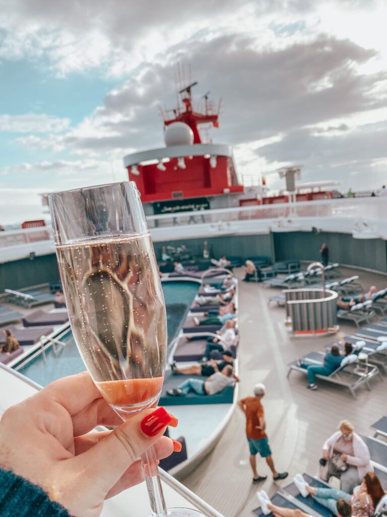 photo holding a glass of champagne infront of the main pool on a cruise ship