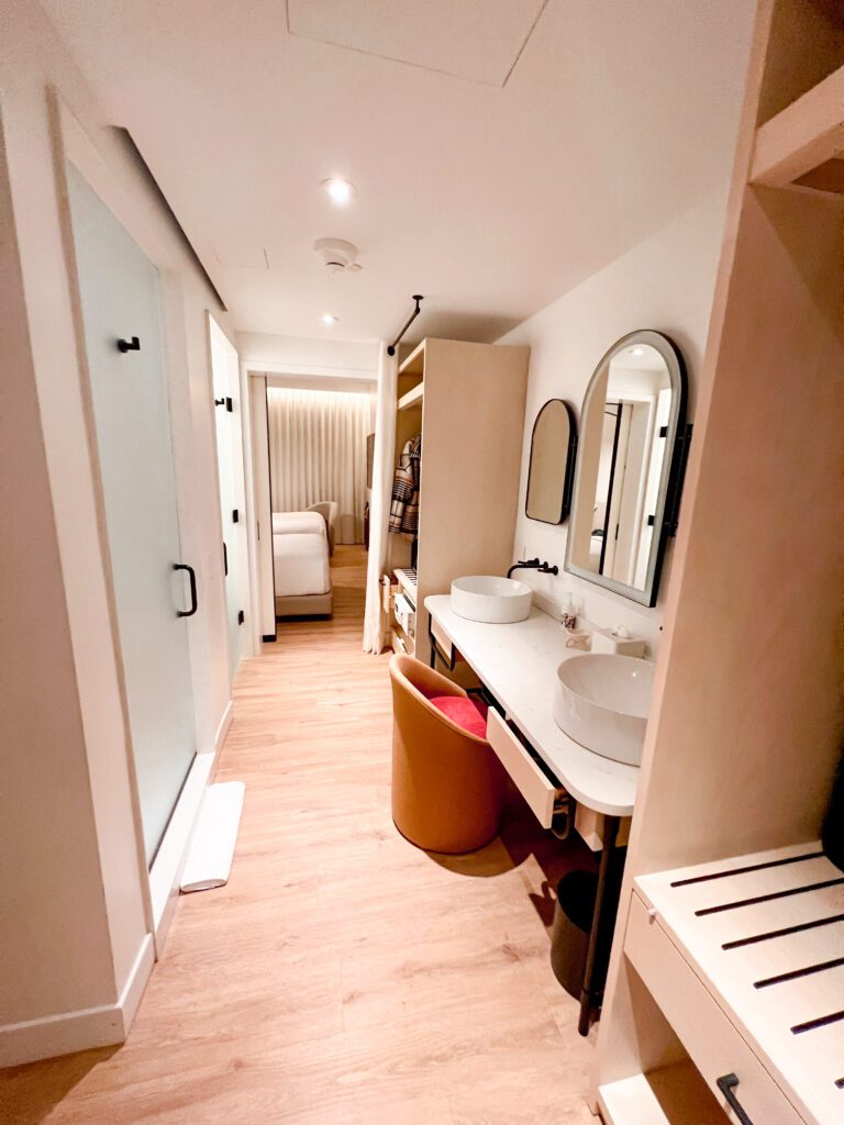 photo of the entrance to the virgin hotel room. As you walk in the vanity area of the bathroom is on your right and the seperate toilet and shower are on your left. The two double beds are ahead of you